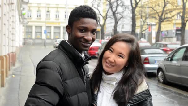 Feliz casal beijo e sorriso para a câmera - homem negro e mulher asiática - rua urbana com carros - cidade — Vídeo de Stock