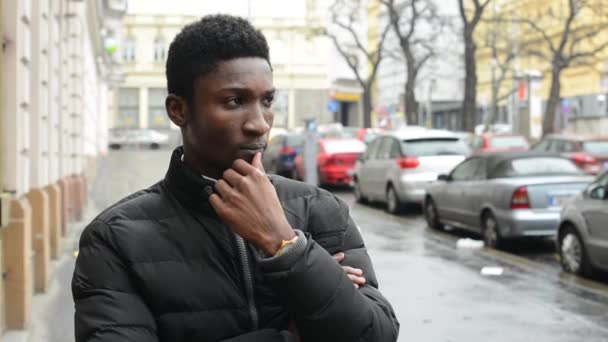Молодий красивий чорний чоловік думає - міська вулиця з машинами - місто — стокове відео