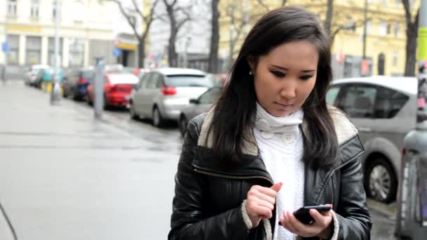 Young attractive asian woman works on smartphone - urban street - city — Stock Video