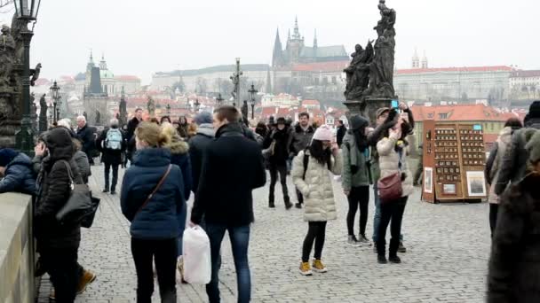 Pessoas caminhando na ponte Charles - cidade - Castelo de Praga no fundo - nublado — Vídeo de Stock
