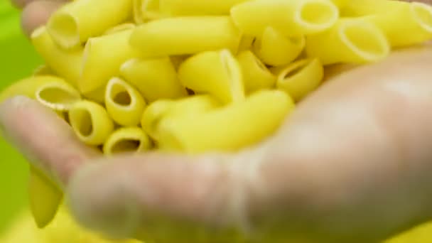 La pasta seca en el contenedor - el primer plano - el trabajador (las manos) controla la calidad de la pasta — Vídeo de stock