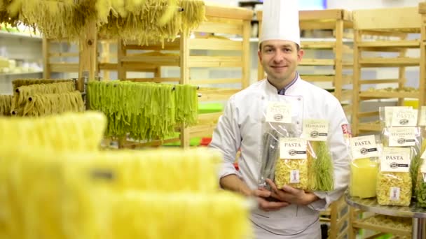 Chef-kok glimlacht naar camera - gedroogde pasta in pakketten — Stockvideo