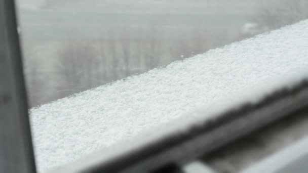 Alféizar de la ventana con nieve - tormenta de nieve - carretera con coches en el fondo - primer plano — Vídeos de Stock