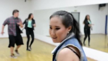Genç çekici Asyalı kadın dans kamera - arka planda dans iki dansçı - binası önünde