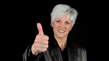 İş orta yaşlı kadın başparmak anlaşması - siyah arka plan - studio - portre üzerinde gösterir.