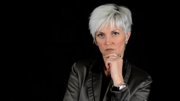 Business middle aged woman looks to camera (thinking) - black background - studio — Stock Video