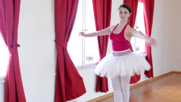 Jonge ballerina dansen in de hal en kijken naar de camera - rode gordijn — Stockvideo