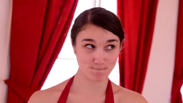 Young attractive woman doing funny grimaces - interior - red curtain - closeup — Stock Video