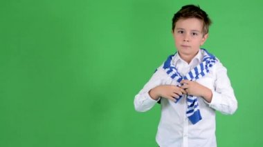 Genç yakışıklı çocuk çocuk onun boyun ve gülümsüyor kamera - yeşil ekran - studio için bir kazak bağları