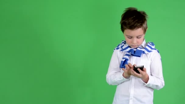 Young handsome child boy works on smartphone (text messaging) - green screen - studio — Stock Video