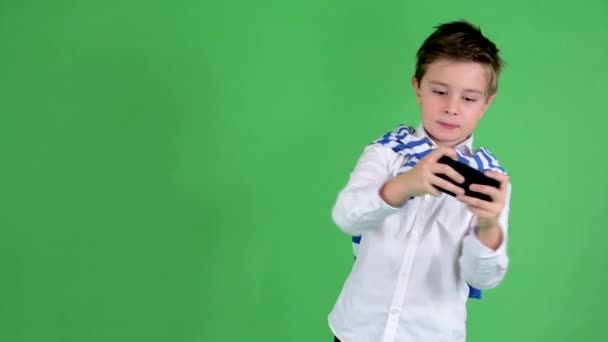 Young handsome child boy plays game on smartphone - green screen - studio — Stock Video