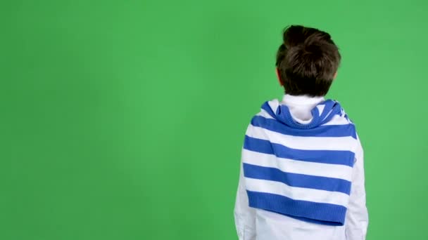 Chłopiec młody przystojny dziecko rozgląda się w okolicy (tył stoi chłopiec) - zielony ekran - studio — Wideo stockowe