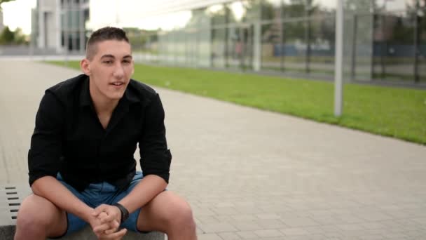 Joven hombre guapo habla a la cámara (entrevista) - calle en la ciudad — Vídeos de Stock