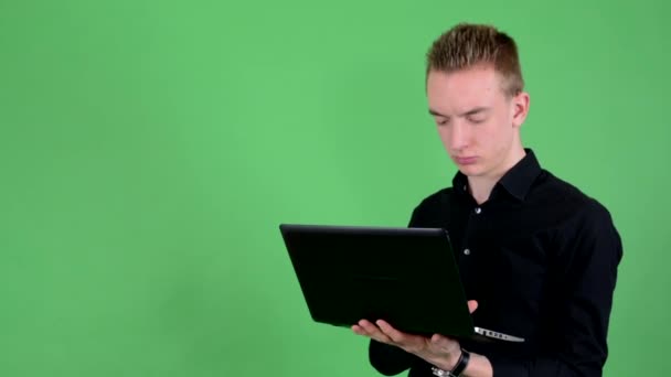Joven hombre guapo trabaja en portátil - pantalla verde - estudio — Vídeo de stock
