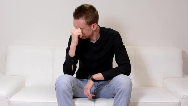 Young handsome man sitting on sofa and stressed out — Stock Video