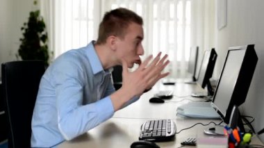 Genç yakışıklı adam masaüstü bilgisayarında çalışıyor ve adam kızgın.