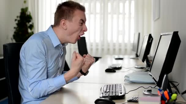 Jovem homem bonito trabalha no computador desktop e gritar com alegria no escritório — Vídeo de Stock