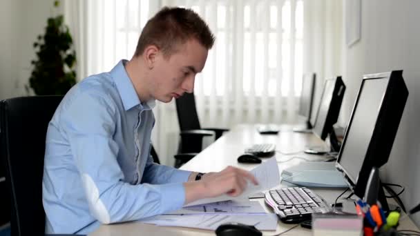 Junger gutaussehender Mann arbeitet am Desktop-Computer und liest Dokument im Büro — Stockvideo