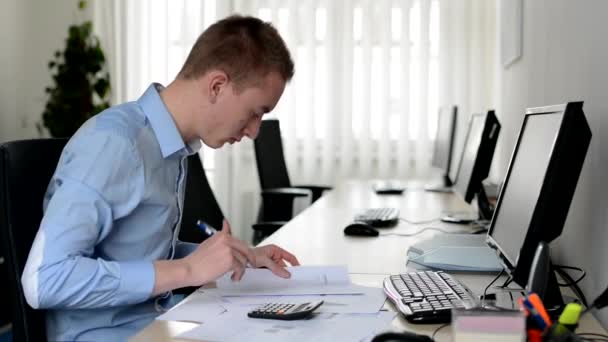 Dolgozó ember az irodában-írásban papíron tollal és számolás egy számológépet-dokumentumok — Stock videók