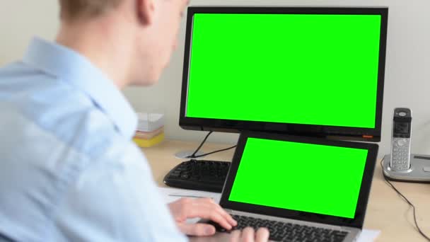 Man works on desktop computer and laptop in the office - green screen — Stock Video