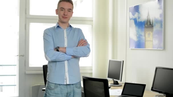 Junger schöner Mann steht im Büro und lächelt in die Kamera — Stockvideo