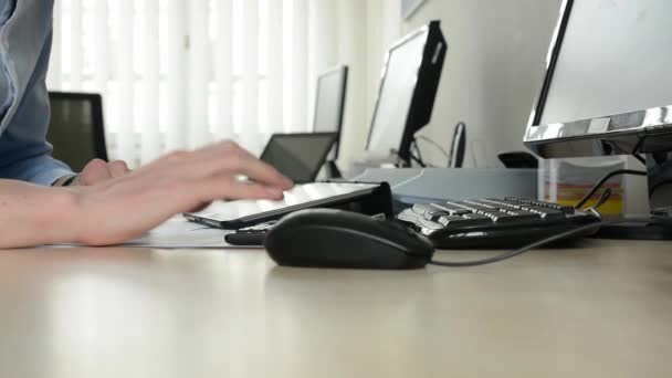 Молодий чоловік працює на планшеті в офісі крупним планом — стокове відео
