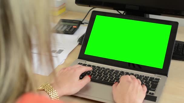 Молодая привлекательная женщина, работающая за ноутбуком в офисе - зеленый экран — стоковое видео
