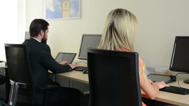 Man and woman working on the computer in the office (workers) - shot on back — Stock Video