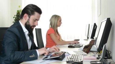 adam tablet üzerinde çalışıyor ve kadın ofiste masaüstü bilgisayarda çalışıyor (işçiler)