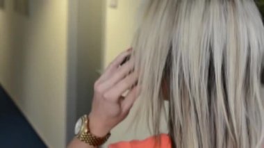 Genç ve çekici bir kadın ofiste yürüyor ve telefonla konuşuyor. Arkasından vurularak.