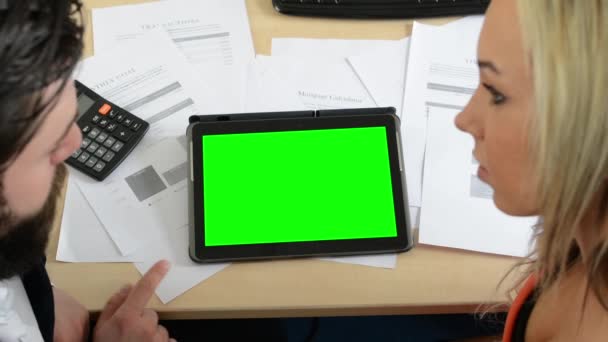 Man och kvinna arbetar på tabletten på kontoret (papper och miniräknare)-grön skärm-med huvuden — Stockvideo
