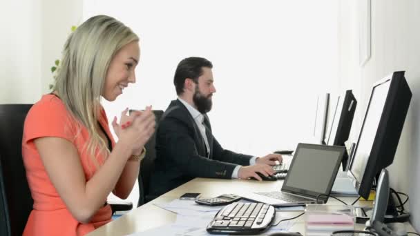 여자가 기뻐하고 남자는 사무실에서 데스크 탑 컴퓨터로 일한다 — 비디오