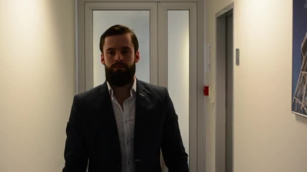 Genç, sakallı, yakışıklı bir adam ofiste dolanıyor. — Stok video
