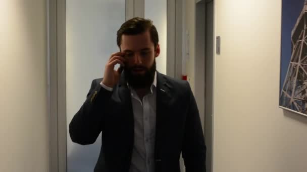 Giovane bell'uomo con la barba piena (hipster) passeggiate e telefono in ufficio - steadicam — Video Stock