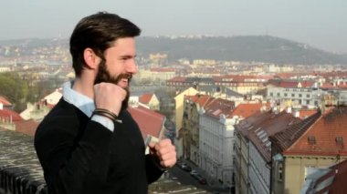 Genç ve sakallı yakışıklı adam (hipster seviniyor) arka planda şehir