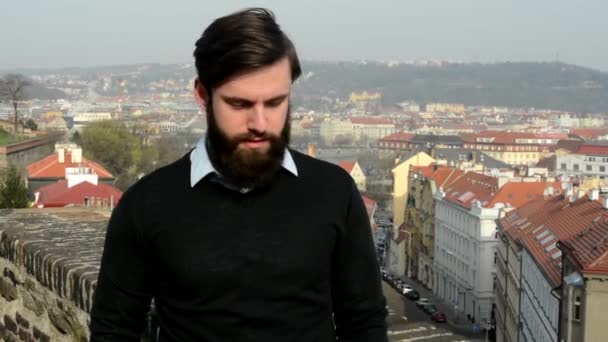Jovem homem bonito com barba cheia (hipster) discordo cidade no fundo — Vídeo de Stock