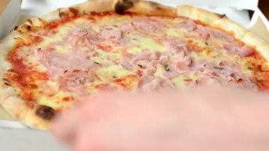 adam pizza ile kutu açar ve bir dilim alır ve yiyor