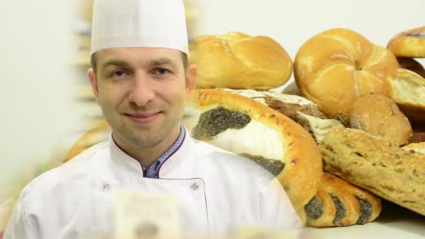 Chef sorri para a câmera - produtos de padaria (pastelaria e bolos) - estúdio de fundo branco — Vídeo de Stock
