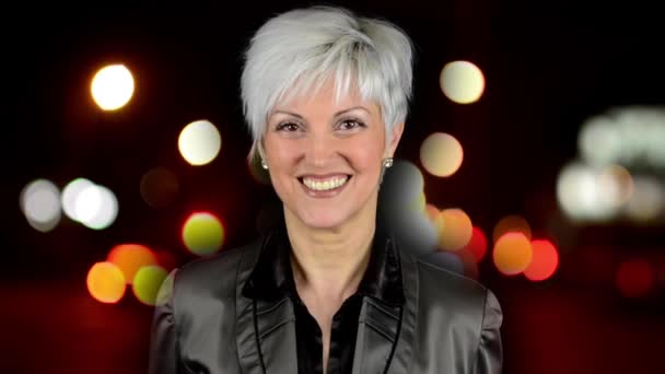 Geschäftsfrau mittleren Alters lächelt - Nacht Stadt - Nacht Straße mit Autos - Lampen - Autoscheinwerfer - extrem verschwommen — Stockvideo