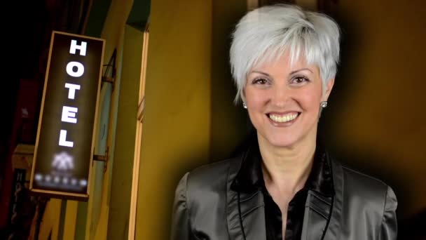Επιχειρηματική μέσης ηλικίας γυναίκα χαμογελά-σύμβολο ξενοδοχείο για την οικοδόμηση-νύχτα — Αρχείο Βίντεο