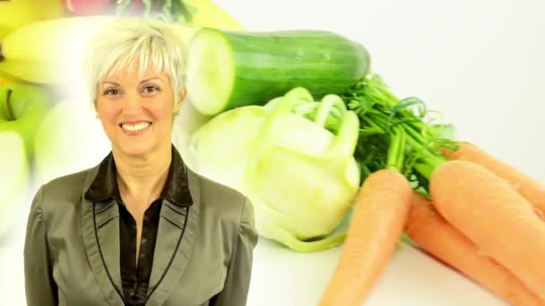 Mujer de mediana edad sonríe - comida saludable - verduras y frutas - estudio de fondo blanco - primer plano — Vídeo de stock