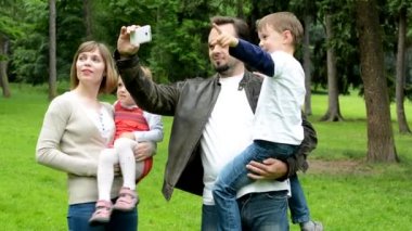 aile (aşık orta çift, sevimli kız ve küçük çocuk) akıllı telefon ile bir fotoğraf çekmek - anıtlar (seyahat) - park