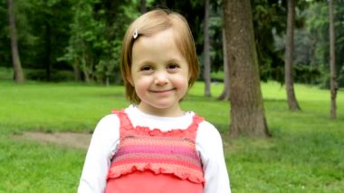 kamera küçük sevimli kız gülümsüyor - arka planda park - park