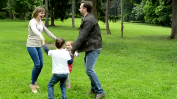 Familie (verliebtes mittleres Paar, süßes Mädchen und kleiner Junge) tanzt im Park im Kreis — Stockvideo