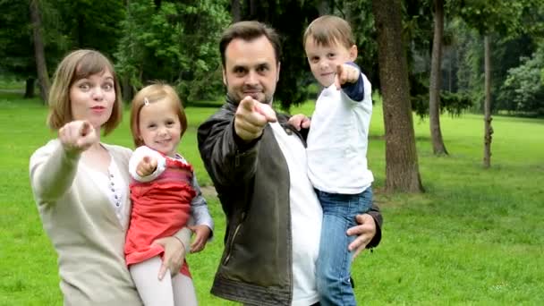 Famille (couple moyen amoureux, fille mignonne et petit garçon) pointent ensemble à la caméra (choisir quelqu'un) - parc — Video
