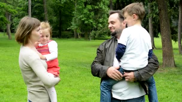 Οικογένεια (μεσαίο ζευγάρι στην αγάπη, χαριτωμένο κορίτσι και μικρό αγόρι) μαζί μιλούν στο πάρκο — Αρχείο Βίντεο