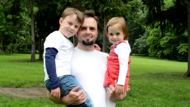 Familia (papá, niño y linda chica) sonrisa a la cámara - parque — Vídeos de Stock