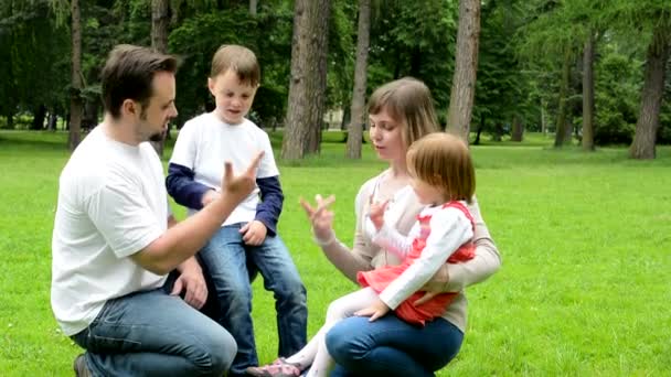 Padres (madre y padre) enseñan a los niños (niño y niña) a contar con los dedos - parque — Vídeos de Stock