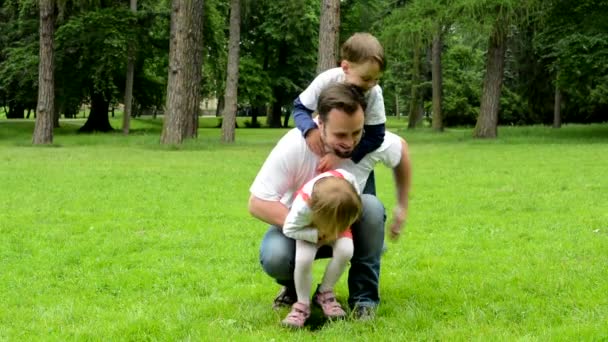 Middle aged father plays with children (boy and girl) - park — Stock Video