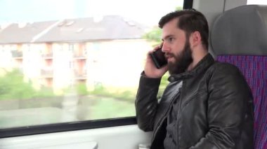 Genç yakışıklı hippi akıllı telefonlu tren ve telefonla seyahat ediyor - şehir - yakın plan